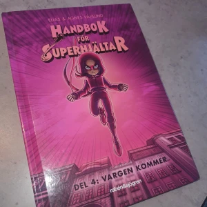 Bok  - Spännande bok 'Handbok för Superhjältar: Del 4: Vargen kommer' av Elias & Agnes Våhlund. Boken har ett iögonfallande lila omslag med en illustration av en superhjälte i centrum. Perfekt för unga läsare som älskar äventyr och superhjältar.