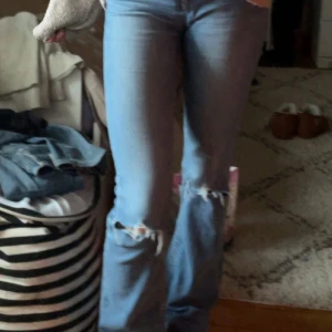 Blå bootcutjeans med slitningar - Snygga blå jeans med slitningar på knäna. De är i bootcut. Fråga om fler bilder!