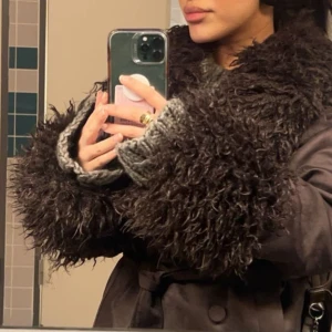 Brun bondad jacka med fuskpälsdetalj - Snygg brun bondad jacka med lyxiga fuskpälsdetaljer på krage och ärmslut. Jackan har ett knytbälte i midjan för en elegant passform. Perfekt för att hålla stilen i kyligare väder. Från NAKD, slutsåld på hemsidan, använd få gånger och i väldigt fint skick, lite stor på mig men så fin