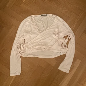 Vit omlottopp från 157 - Säljer en stilren vit omlottopp från 157 i storlek XL. Toppen har långa ärmar och knytband i midjan för en justerbar passform. Perfekt för en avslappnad och chic look. 🌟