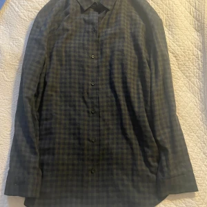 Rutig skjorta från COS - Snygg rutig skjorta från COS i mörkblå och grön färg. Skjortan har långa ärmar och knappar. Perfekt för en stilren look.
