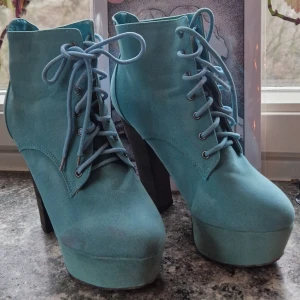 Turkosa platform boots med snörning - Turkosa platform boots med snörning från 2010-talet. Platån gör att de är enkla och bekväma att gå i. Har lite färgvariation / mindre fläckar på mockan men är annars hela och i gott skick.  