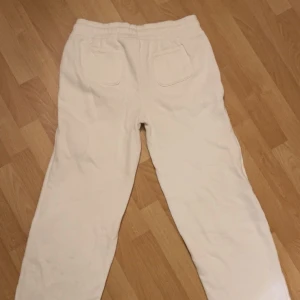 Vita mjukisbyxor med snörning - Säljer ett par bekväma vita mjukisbyxor med snörning i midjan. Byxorna har en loose passform och praktiska fickor fram. Perfekta för en avslappnad stil.