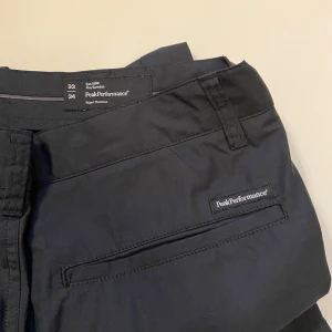 Svarta byxor från Peak Performance - Snygga svarta byxor från Peak Performance med en stilren design. Byxorna har en knapp och dragkedja framtill samt diskreta fickor. Perfekta för en stilren look.