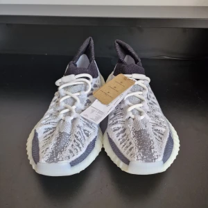 YEEZY 350 V2 CMPCT - Snygga Adidas Yeezy sneakers i en stilren grå och vit färgkombination. Skorna har en stickad ovandel med ett unikt mönster och bekväm snörning. Den ribbade sulan ger både stil och komfort.Har order bekräftelse från Adidas för att bevisa att de är äkta.