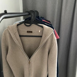 Beige stickad tröja från Stenströms - Säljer en stilren beige stickad tröja från Stenströms med dragkedja framtill. Tröjan har långa ärmar och en ribbad krage samt ribbade muddar vid ärmslut och nederkant. Perfekt för kyligare dagar! Nypris : 3200 kr. "Varan sitter som xs pga Liten krympning i tvätten, näst intill ingen skillnad."