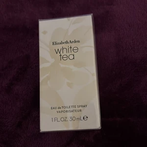 White Tea Eau de Toilette från Elizabeth Arden - Säljer en elegant flaska av Elizabeth Arden White Tea Eau de Toilette. Flaskan har en stilren design med en vit och transparent gradient och en fyrkantig vit kork. Perfekt för den som älskar fräscha och lätta dofter.
