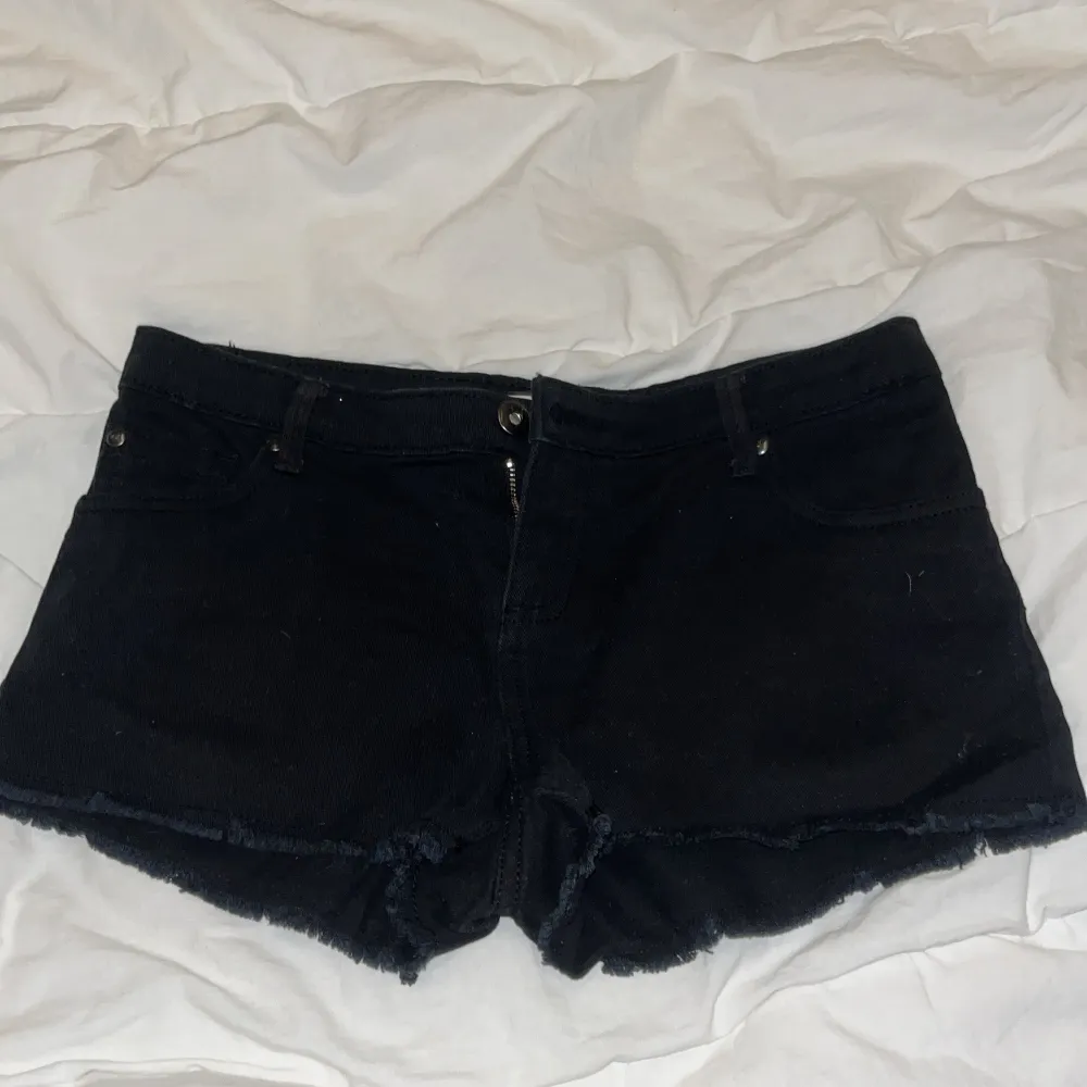 Säljer ett par svarta jeansshorts i bra skick. De har en snygg fransig kant och är perfekta för sommaren. Shortsen har en knapp och dragkedja framtill. Passar till både vardag och fest!. Shorts.