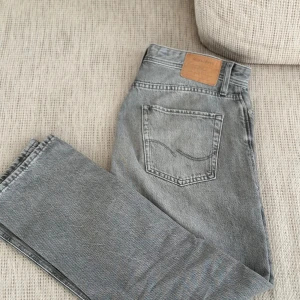 Grå jeansbyxor - Säljer ett par snygga grå jeansbyxor i bra skick. De har en klassisk femficksdesign och en läderpatch vid midjan. Perfekta för både vardag och fest! 🖤