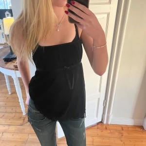 Svart linne med rosett - Säljer en svart jätte gullig topp med smala axelband. Väldigt bra skick och knappt använd💕