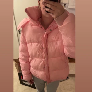 Rosa pufferjacka från BikBok - Säljer en superfin rosa pufferjacka från BikBok i storlek L. Jackan är perfekt för kyliga dagar med sin mysiga och varma design. Den har en dragkedja framtill och en stor huva för extra skydd mot väder och vind. Luvan är också avtagbar med dragkedja. Skönaste jackan jag har, men har blivit för stor!Perfekt för både höst och vinter! 💖den är lite smutsig på tyget runt handlederna o få fläckar på övriga jackan men ska gå att tvätta! Inget jag testat. Skicka bud!!😀🙌🏻
