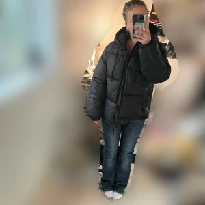Svart pufferjacka - Säljer en svart pufferjacka i mycket bra skick. Den är perfekt för kalla vinterdagar med sin tjocka vaddering och långa ärmar. Jackan har en dragkedja framtill och en hög krage för extra värme. Den är oversized och ger en cool look. Passar perfekt till jeans och sneakers för en avslappnad stil.