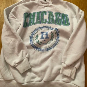 Vit sweatshirt med Chicago-tryck - Säljer en vit sweatshirt från Sister i storlek XS. Den har ett coolt Chicago-tryck i grönt och blått på framsidan. Perfekt för en avslappnad stil eller en dag på stan. Tröjan är i bra skick och superbekväm med ribbade muddar vid ärmslut och nederkant.
