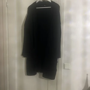 Svart lång kappa/ kofta  - Säljer en stilren svart lång kappa i mycket bra skick. Perfekt för höst och vinter med sin klassiska design. Den har långa ärmar och en skön passform som passar de flesta tillfällen. Ett måste i garderoben för den som vill hålla sig varm och snygg!