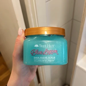 Tree Hut Blue Lagoon Shea Sugar Scrub - Säljer en härlig Blue Lagoon Shea Sugar Scrub från Tree Hut. Den har en fräsch turkos färg och kommer i en burk med guldlock. Perfekt för att exfoliera och återfukta huden med sheasmör och sockerkristaller. Doftar underbart och ger en lyxig spa-känsla hemma. Perfekt för att fräscha upp huden. Endast provad 