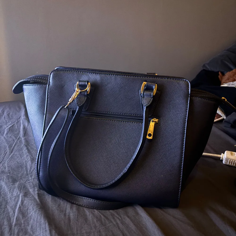 Mörkblå  svart handväska från Michael Kors i mycket bra skick. Väskan har guldfärgade detaljer. Säljer då den inte kommer till användning! Pris kan diskuteras privat!. Väskor.