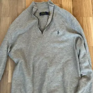 Säljer en stilren grå tröja från Polo Ralph Lauren. Den har en dragkedja vid halsen och det klassiska logotypbroderiet på bröstet. Perfekt för både vardag och lite finare tillfällen. Tröjan är i bra skick och passar perfekt till höst och vår.