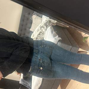 Säljer ett par snygga blå jeans i bra skick. De är lågmidjade och är bootcut. Fickorna är broderade med coola detaljer som ger en unik look. Perfekta för både vardag och fest!