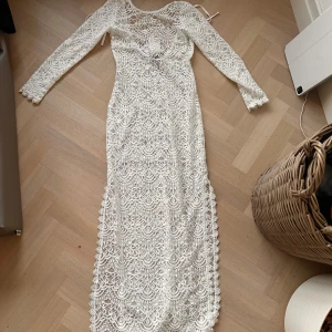 Vit spetsklänning från H&M - Säljer en elegant vit långklänning i spets från H&M. Klänningen har långa ärmar och ett vackert mönster som ger en romantisk känsla. Perfekt för sommarens fester eller en speciell dag. Klänningen är helt oanvänd då den köptes i fel storlek, säljer den för 40kr:)