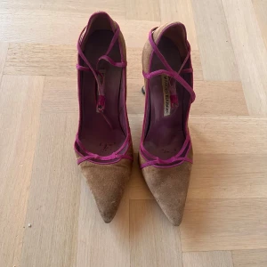 Bruna pumps från Manolo Blahnik - Säljer ett par eleganta bruna pumps från Manolo Blahnik med spetsig tå och klack i storlek 38 1/2. De har snygga rosa detaljer och är perfekta för en festlig kväll. Skorna är lite slitna pga mke användning (se sista bilden) därav säljs de för 650kr:)