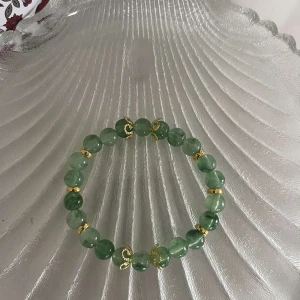 Grönt armband med gulddetaljer - Snyggt armband med gröna pärlor och guldfärgade detaljer. Perfekt för att ge en touch av färg och elegans till din outfit. Passar både till vardags och festliga tillfällen.