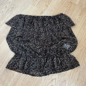 Leopardmönstrad offshoulder-top - Säljer en snygg leopardmönstrad offshoulder-top i lätt och luftig design från Gina Tricot. Perfekt för en utekväll eller sommarfest! Toppen har en elastisk kant vid axlarna och midjan för en bekväm passform. 🐆✨