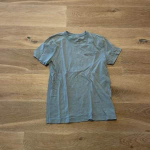 Grön  t-shirt - Säljer en enkel och stilren grön t-shirt i bomull. Perfekt för vardagsbruk eller som basplagg. Den har en normal passform och korta ärmar, vilket gör den bekväm och lätt att matcha med andra kläder.