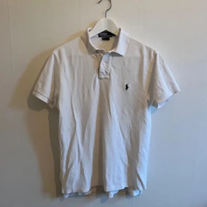 Vit pikétröja från Ralph Lauren - Säljer en klassisk vit pikétröja från Ralph Lauren i bra skick. Den har en broderad logga på bröstet och korta ärmar. Perfekt för en stilren och avslappnad look. Passar både till vardags och fest!