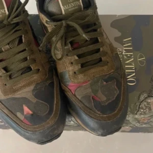 Valentino Garavani sneakers i camouflage - Säljer ett par snygga Valentino Garavani sneakers i camouflage. Skorna har en cool mix av gröna, bruna och röda nyanser med snörning. Använda men i bra skick. Passar perfekt för höst och vår!