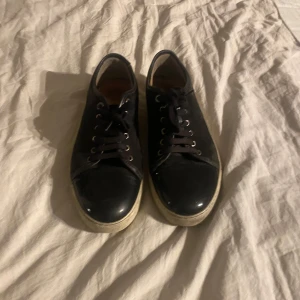 Svarta Lanvins - Säljer ett par svarta Lanvins i bra skick. De har en klassisk design med snörning och en vit sula som ger en snygg kontrast. Perfekta för både vardag och fest! Storlek 45