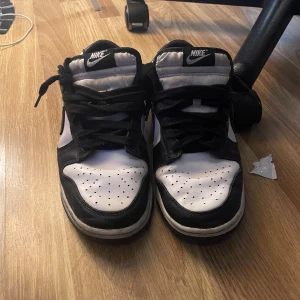 Svartvita Nike sneakers - Säljer ett par klassiska svartvita Nike sneakers i bra skick. De har en snygg kontrast mellan svart och vitt med den ikoniska Nike-loggan på sidan. Perfekta för vardagsbruk eller en avslappnad stil. Skorna har snörning och en bekväm passform.