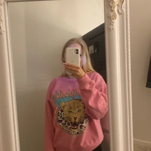 Rosa sweatshirt med leopardtryck - Säljer en cool rosa sweatshirt med ett stort leopardtryck på framsidan. Tröjan har långa ärmar och en avslappnad passform, perfekt för en casual look. Den är i bra skick och passar perfekt för höst och vår. Perfekt för dig som vill sticka ut lite extra! 🐆💖