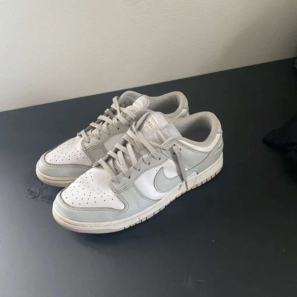 Säljer ett par stilrena Nike Dunk i grått och vitt. Skorna har en klassisk design med snörning och är i bra skick. Perfekta för vardagsbruk eller en avslappnad stil. Pris går att diskutera . Skor.