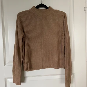 Beige stickad tröja - Säljer en supermysig beige stickad tröja i storlek S. Perfekt för höst och vinter med sin ribbade design och långa ärmar. Den har en hög krage som håller dig varm och stilen är både enkel och trendig. Passar perfekt till jeans eller kjol för en avslappnad look. 🧶✨