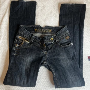 Svarta jeans från Timezone - Säljer ett par svarta jeans från Timezone i bra skick. De har coola detaljer som slitningar och dragkedjor på bakfickorna. Perfekta för en avslappnad stil. BOOTCUT OCH LÅGMIDJA!!!