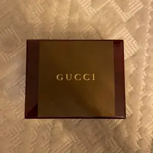 Säljer en elegant Gucci-klocka i originalförpackning. Klockan har ett unikt bi-motiv på urtavlan och ett klassiskt svart och rött armband. Perfekt för både vardag och fest. Kommer med originaldokumentation.