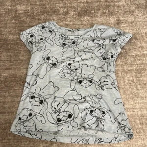 Grå/blå t-shirt med stitch på - Säljer en grå t-shirt från Primark. Man ser inte vad det är för storlek men jag skulle gissa på S-M. Den är kortärmad och perfekt för vardagsbruk. T-shirten är i bra skick och passar perfekt till jeans eller shorts. Perfekt för dig som gillar en avslappnad stil! 