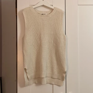 Vit stickad väst från H&M - Säljer en mysig vit stickad väst från H&M. Perfekt för lager-på-lager under höst och vinter. Den har en ribbad kant vid ärmhålen och nederkanten. Västen är i mycket bra skick och passar till både vardag och fest.