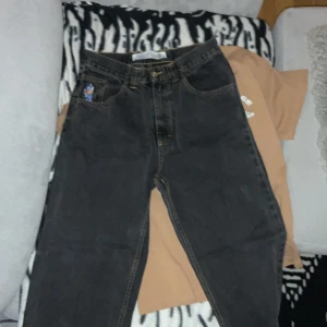 Svarta jeans från 93 Denim - Säljer ett par svarta jeans från 93 Denim i bra skick. De har en cool broderad detalj på fickan och en gul etikett med '93!' på baksidan. Jeansen har en klassisk femficksdesign och stängs med dragkedja och knapp. Perfekta för en avslappnad stil!