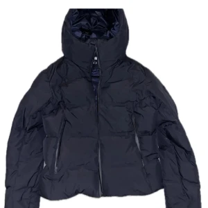 Svart dunjacka från Uniqlo - Säljer en svart dunjacka från Uniqlo i mycket bra skick. Den är perfekt för vintern med sin varma och quiltade design. Jackan har en dragkedja framtill och långa ärmar. Den är både stilren och funktionell, perfekt för kalla dagar. Passar både till vardags och lite finare tillfällen. Riktiga priset 1700kr 