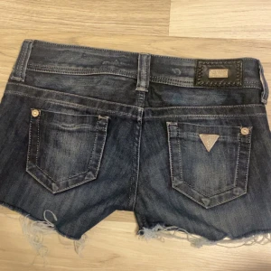 Mörkblå jeansshorts från Guess - Säljer ett par snygga mörkblå jeansshorts från Guess Premium. De har en fransig kant och klassiska femficksdesign. Perfekta för sommaren och festivaler! 🕶️