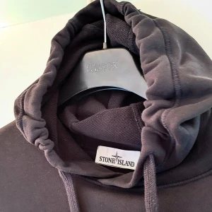 Svart hoodie från Stone Island - Svart Stone Island Hoodie i väldigt fint skick säljes. Givetvis äkta - kvitto finns!  Köpt på Stone Island butiken i Stockholm City för ett par år sedan. Säljes pga ej kommit till användning.   Jag är 185cm och väger ca 87kg och den sitter bra på mig.