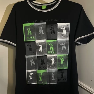 Svart t-shirt från Hugo Boss med grafiskt tryck - Säljer en svart t-shirt från Hugo Boss i mycket bra skick. Den har ett coolt grafiskt tryck med bilder i grönt, vitt och svart på framsidan. T-shirten har korta ärmar och en rund halsringning med grå kant. 