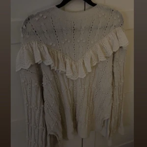 Vit stickad tröja med volangdetaljer - Superfin vit stickad tröja med volangdetaljer och ett snyggt hålmönster. Perfekt för höst och vinter, den är både mysig och stilren. Långärmad med en unik design som verkligen sticker ut. Passar perfekt till både jeans och kjol! Den är från Zara och tror inte den säljs längre💞