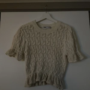 Vit stickad topp från Zara - Säljer en superfin vit stickad topp från Zara. Den har korta ärmar med volangdetaljer och en söt volangkant nedtill. Perfekt för vår och sommar men även en middag! Den är använd ett fåtal gånger och därav inga defekter! Den är mindre i storleken så skulle säga att den passar en xs/s!