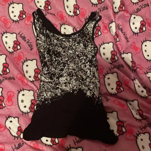 Svart paljettlinne från Vero Moda - Snyggt svart linne från Vero Moda i storlek XS. Toppen är täckt med glittriga paljetter liknande glitter framtill som ger en festlig look. Perfekt för en utekväll eller fest! Baksidan är enkel och utan paljetter.