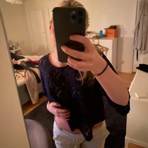 Mörkblå spetsblus - Säljer en elegant mörkblå spetsblus, Blusen har trekvartsärmar och ett vackert blommigt mönster. Perfekt för både vardag och festliga tillfällen. Den är i mycket bra skick och redo för en ny ägare!