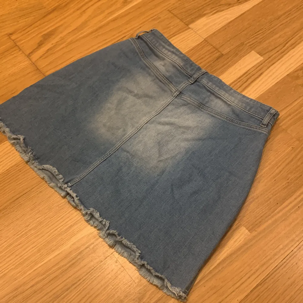 Säljer en snygg jeanskjol från Lindex i storlek EUR 170. Kjolen har en klassisk blå denimfärg med knappar framtill och en fransig nederkant för en cool look. Perfekt för både vardag och festliga tillfällen. 🦋(liten fläck med av svart bläck). Kjolar.