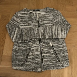 Gråmelerad jacka från Gina Tricot - Säljer en snygg gråmelerad jacka från Gina Tricot i storlek XS. Jackan har en dragkedja framtill och två snedställda dragkedjor som detaljer. Perfekt nu till vintern. Passar både till vardags och lite finare tillfällen.