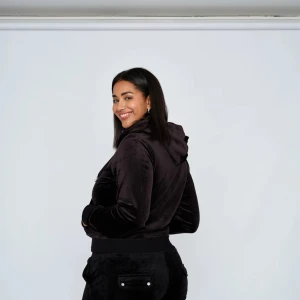 Svart velour hoodie från Juicy Couture - Säljer en supermjuk och bekväm svart velour hoodie från Juicy Couture. Perfekt för en avslappnad stil med dragkedja och huva. Den har en liten ficka med knappdetalj på framsidan. Passar perfekt för mysiga dagar hemma eller en casual dag ute. 🖤TRÖJAN ÄR S OCH BYXOR M